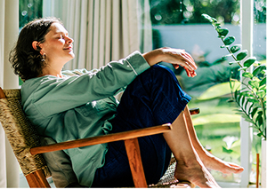 Woman relaxing at home in a chair surrounded by plants