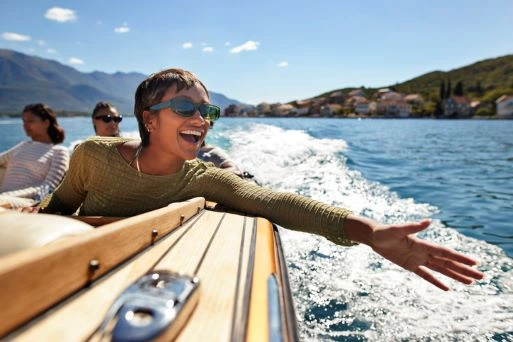 A smiling woman riding in a boat looks out across the water.