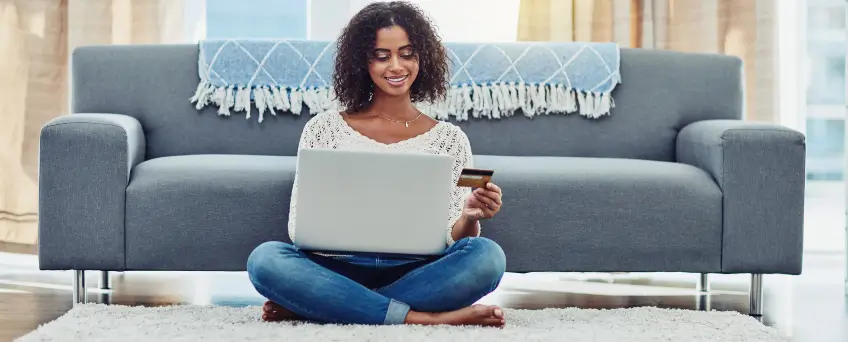 Woman Sitting on Floor with Laptop on lap and credit card in hand