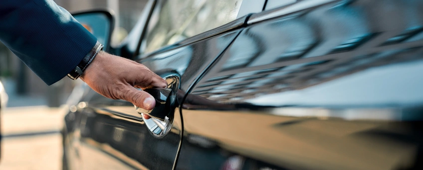A hand reaches to open a car door.