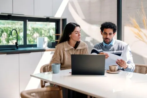 A couple checks their finances in their kitchen.